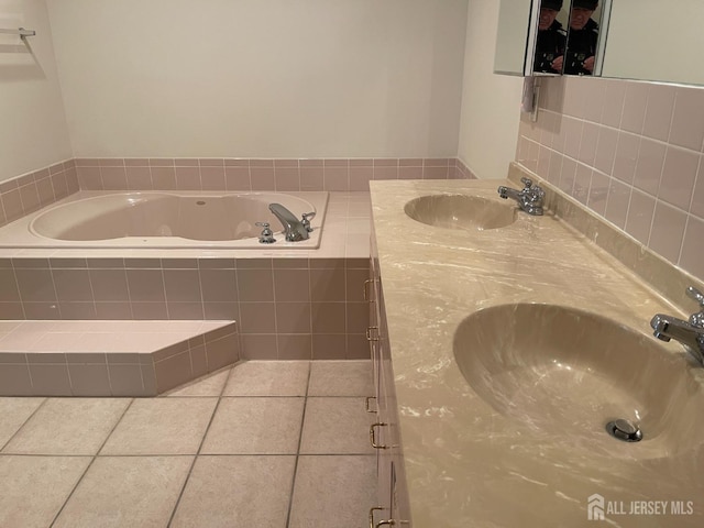 bathroom featuring tiled tub, vanity, and tile patterned flooring