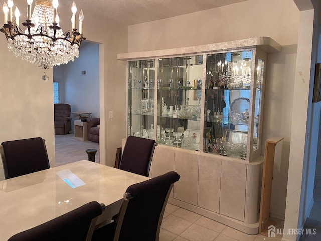 dining area with a notable chandelier, a textured ceiling, and light tile patterned flooring