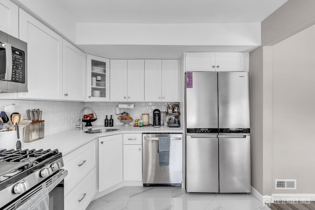 kitchen featuring appliances with stainless steel finishes, a sink, light countertops, decorative backsplash, and white cabinets