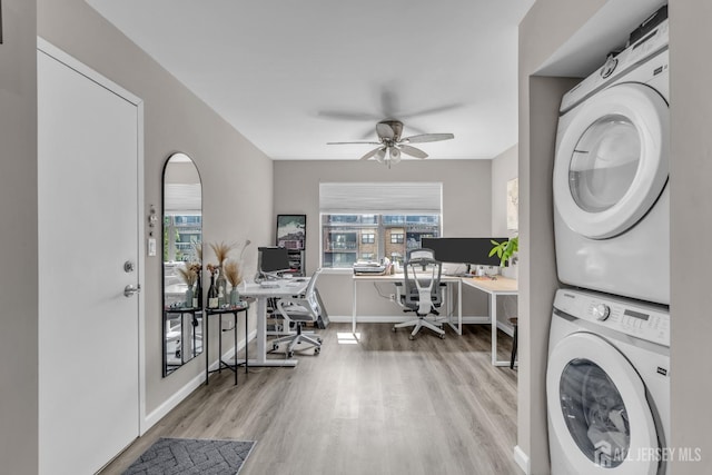 clothes washing area with stacked washer / drying machine, wood finished floors, an office area, and healthy amount of natural light