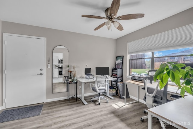 office with ceiling fan, light wood finished floors, baseboards, and arched walkways