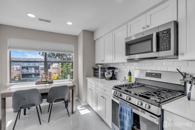 kitchen with stainless steel appliances, decorative backsplash, white cabinetry, light countertops, and recessed lighting
