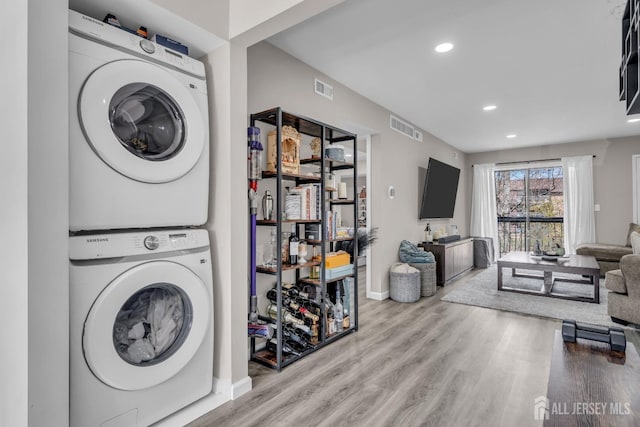clothes washing area featuring stacked washer / dryer, wood finished floors, recessed lighting, and baseboards