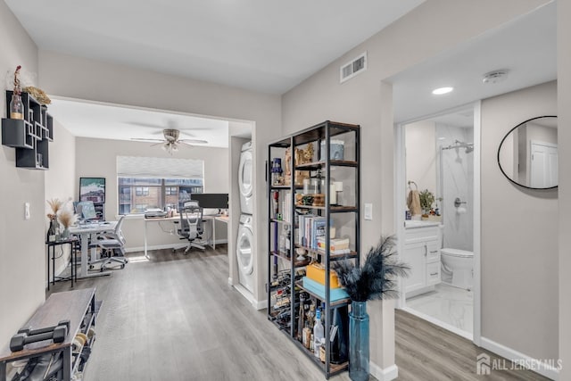 hallway featuring an office area, estacked washer and dryer, light wood finished floors, baseboards, and recessed lighting