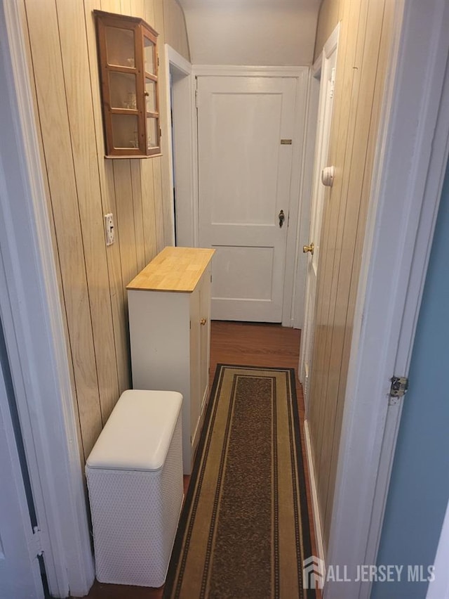 hall featuring wooden walls and dark wood finished floors