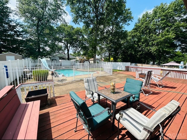 wooden deck featuring a fenced in pool, outdoor dining space, and a fenced backyard