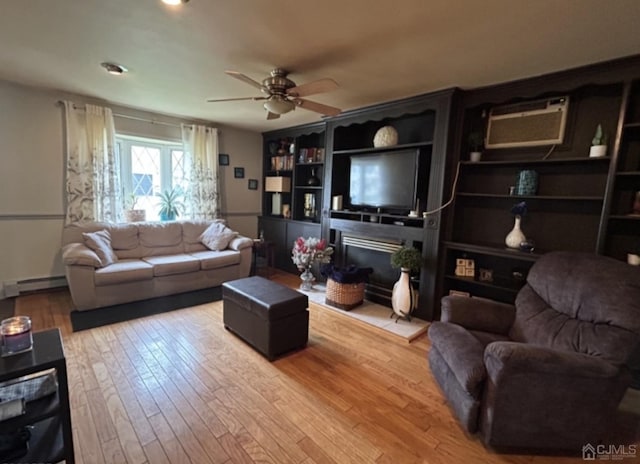 living area with light wood-style flooring, a baseboard heating unit, a fireplace, a ceiling fan, and a wall mounted AC