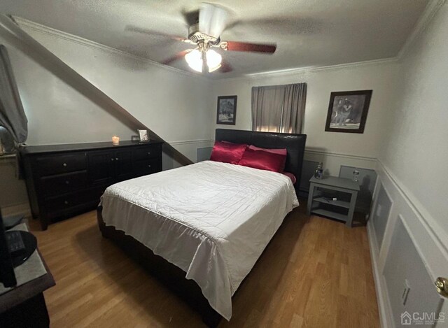 bedroom with hardwood / wood-style flooring, crown molding, a textured ceiling, and ceiling fan