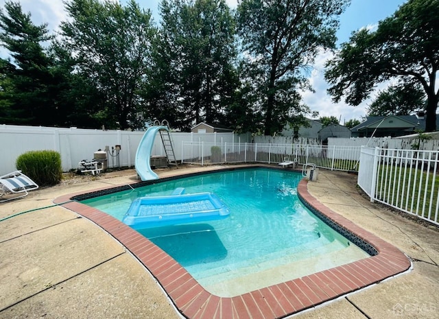 view of pool featuring a fenced in pool, a patio, a water slide, a fenced backyard, and a diving board