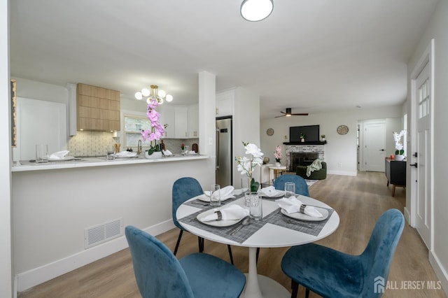 144 Elm St, Dover, NJ 07801 - dining area with light wood-style floors, a fireplace, and a ceiling fan