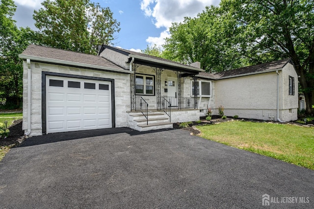144 Elm St, Dover, NJ 07801 - ranch-style home with a garage, covered porch, a front yard, asphalt driveway, and stone siding