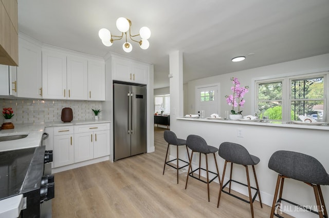 144 Elm St, Dover, NJ 07801 - kitchen with high end fridge, a kitchen breakfast bar, white cabinets, and tasteful backsplash