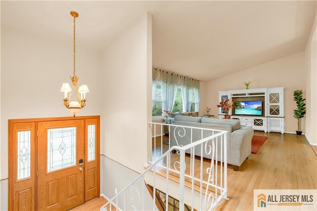 entrance foyer featuring vaulted ceiling, a chandelier, wood finished floors, and baseboards