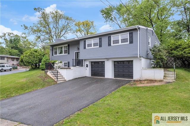 raised ranch featuring a garage, driveway, and brick siding