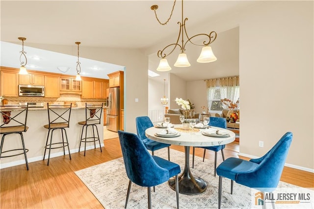 dining space with lofted ceiling, light wood finished floors, and baseboards