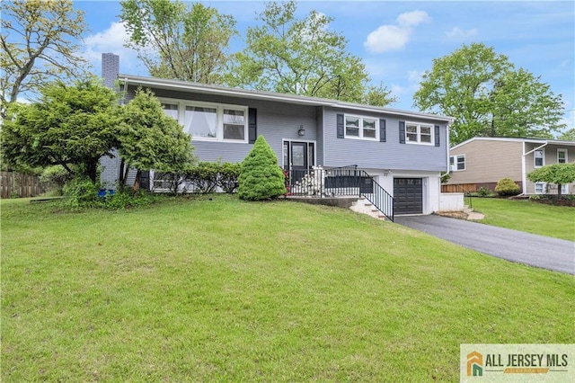 split foyer home with a garage, driveway, a chimney, and a front yard