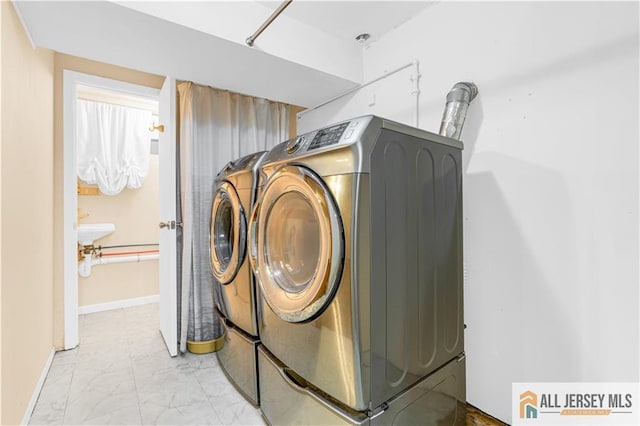 washroom featuring washing machine and dryer, light marble finish flooring, and baseboards