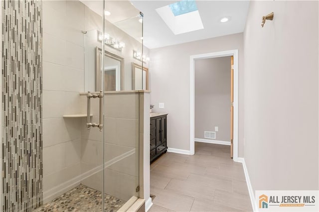 full bathroom featuring a skylight, a shower stall, vanity, baseboards, and recessed lighting