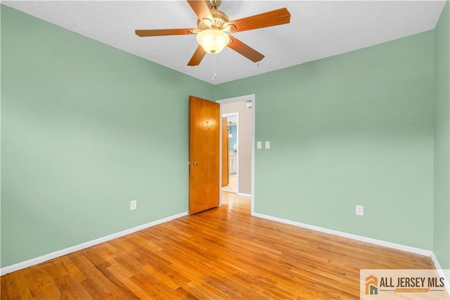 empty room featuring baseboards, wood finished floors, and ceiling fan