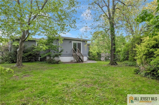 rear view of property featuring entry steps and a lawn