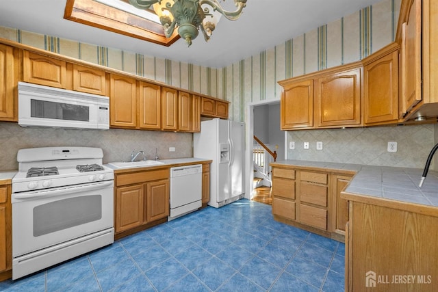 kitchen with white appliances, wallpapered walls, backsplash, a chandelier, and a sink