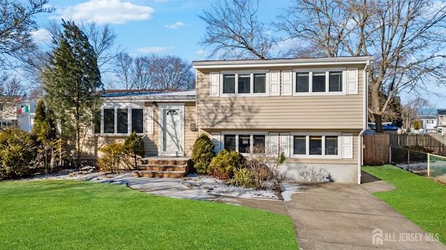 tri-level home with a front yard and fence