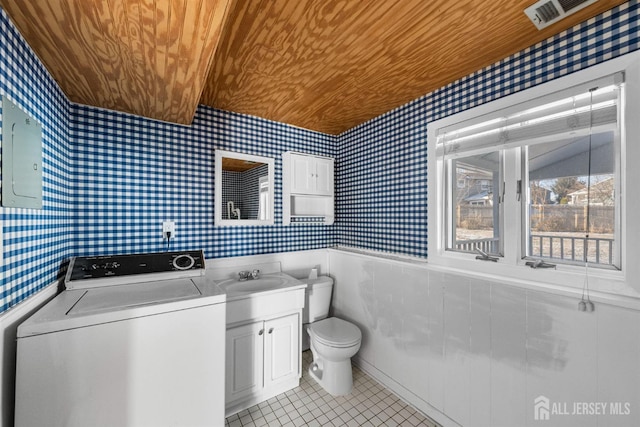 half bathroom featuring a wainscoted wall, wooden ceiling, washer / dryer, and wallpapered walls