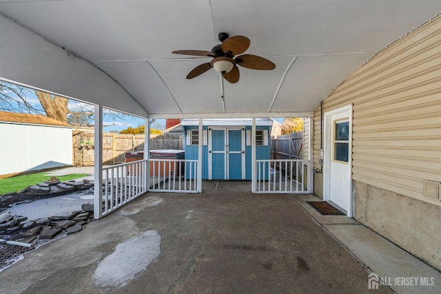 view of patio / terrace with a hot tub, a fenced backyard, a storage unit, and an outbuilding