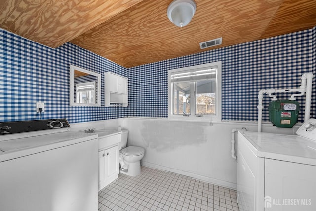 bathroom with wood ceiling, a wainscoted wall, independent washer and dryer, and wallpapered walls