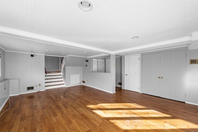 unfurnished living room featuring stairway, baseboards, visible vents, and wood finished floors