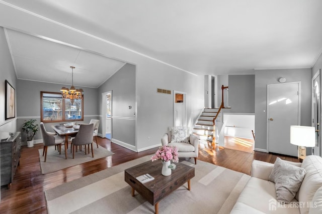 living area featuring visible vents, lofted ceiling, stairway, wood finished floors, and a chandelier