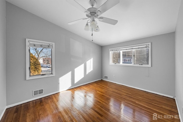 empty room featuring baseboards, visible vents, and wood finished floors