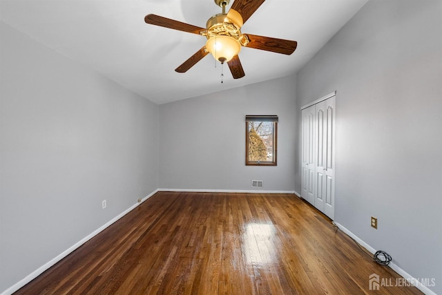 unfurnished room featuring baseboards, visible vents, a ceiling fan, dark wood-type flooring, and vaulted ceiling