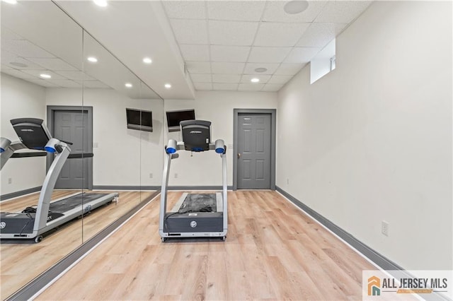 workout room with a paneled ceiling, light wood-style floors, baseboards, and recessed lighting