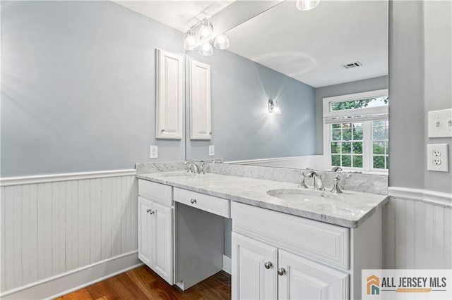 full bath featuring a wainscoted wall, double vanity, wood finished floors, and wooden walls