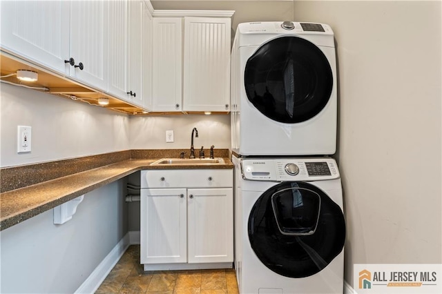 laundry area featuring estacked washer and dryer, cabinet space, and baseboards