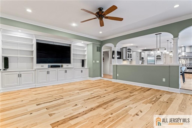 unfurnished living room featuring light wood-style floors, ornamental molding, arched walkways, a ceiling fan, and ornate columns