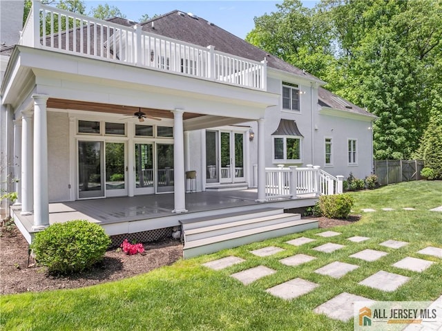 rear view of property featuring a balcony, a ceiling fan, stucco siding, and french doors