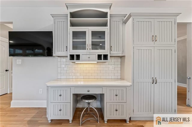 office space featuring baseboards, light wood-type flooring, and built in study area