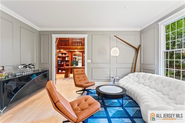 living area featuring a decorative wall, light wood-type flooring, and ornamental molding
