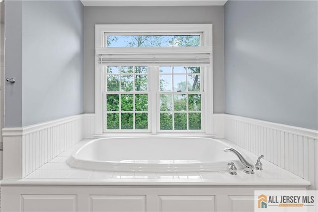 bathroom with a garden tub and wainscoting