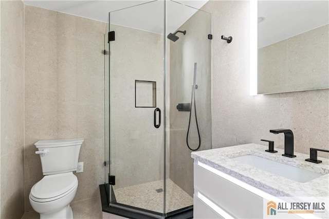 full bath with a stall shower, toilet, and vanity