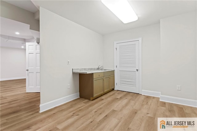 bar area featuring baseboards, a sink, light wood-style floors, and recessed lighting
