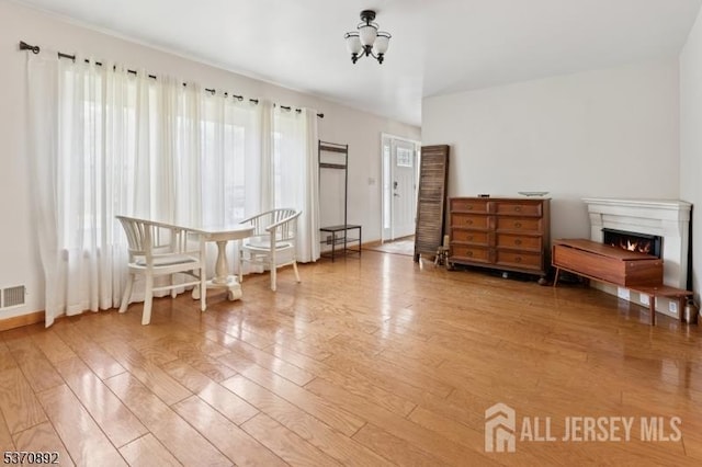 101 Pergola Ave, Monroe, NJ 08831 - sitting room with light wood-style flooring, a chandelier, and a warm lit fireplace