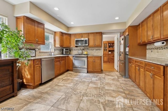 101 Pergola Ave, Monroe, NJ 08831 - kitchen featuring stainless steel appliances, brown cabinets, decorative backsplash, recessed lighting, and light stone countertops