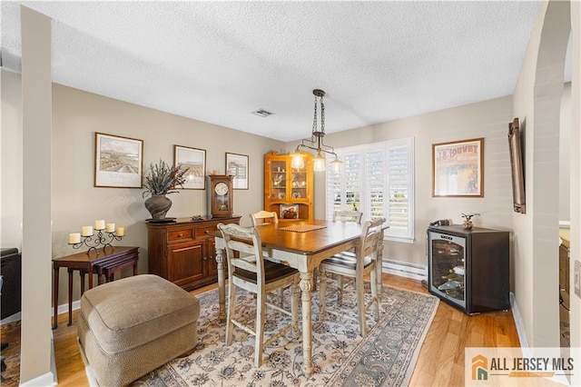 dining room featuring visible vents, baseboards, light wood-style floors, and a textured ceiling