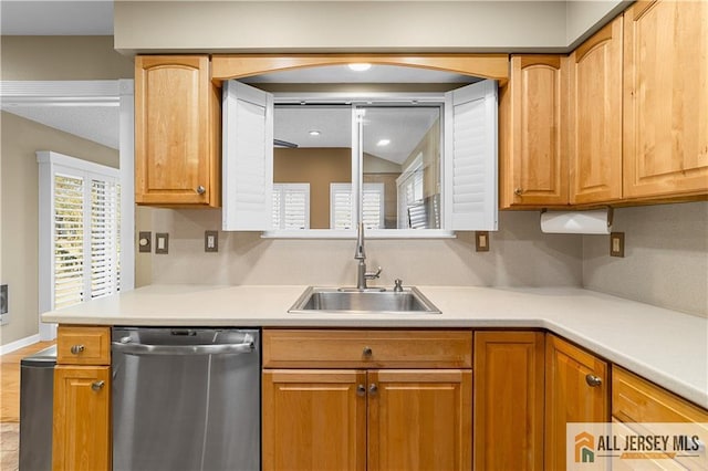 kitchen with a sink, baseboards, stainless steel dishwasher, and light countertops