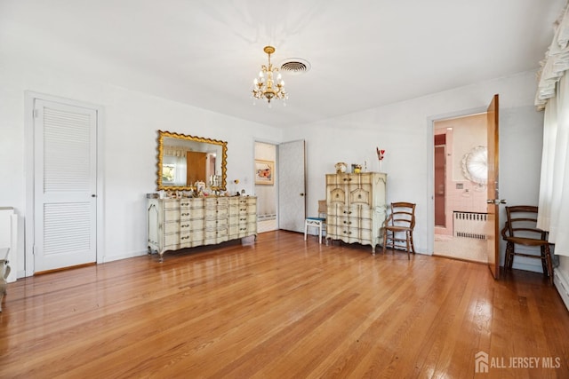 bedroom with wood finished floors, a chandelier, radiator, baseboards, and visible vents