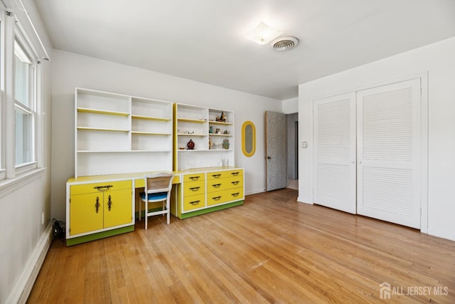 unfurnished office with a baseboard radiator, visible vents, light wood-style flooring, and baseboards