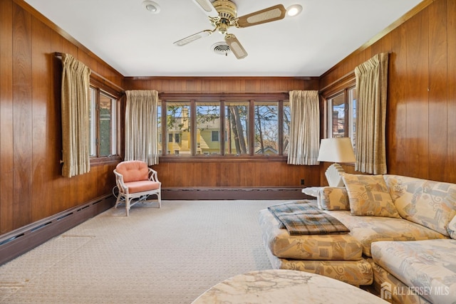 carpeted living area with a baseboard radiator, wooden walls, and a wealth of natural light